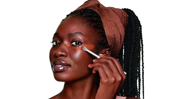 photo of woman putting concealer on